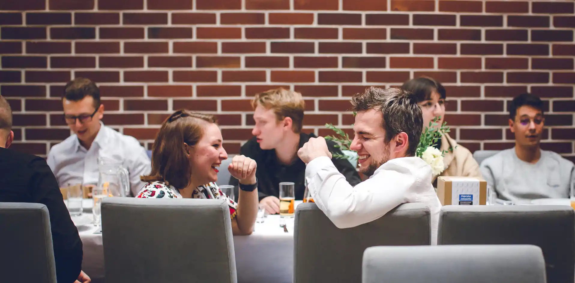 a group of people sitting at a table at a party, laughing