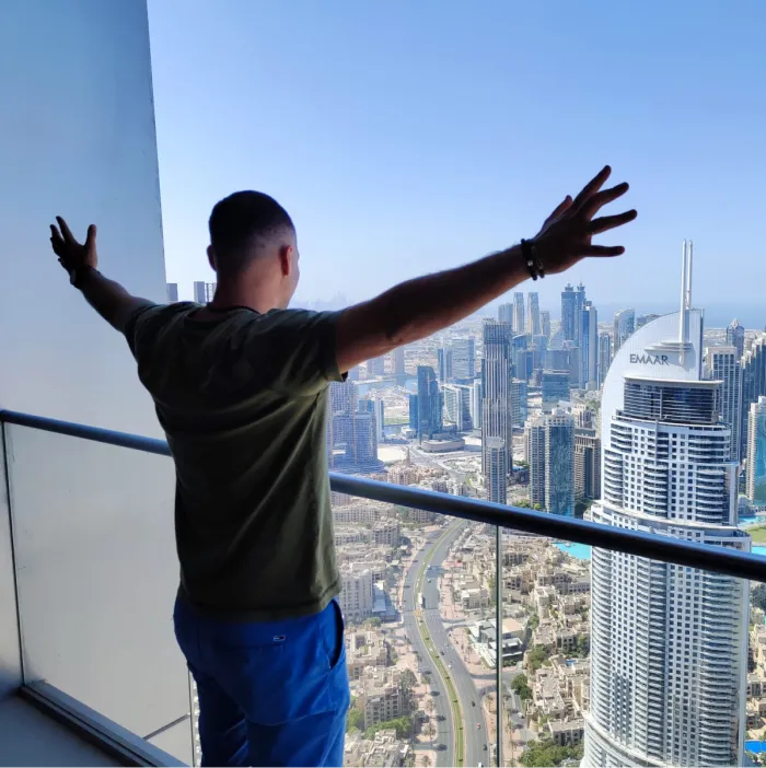 man spreading his arms in front of a landscape of skyscrapers